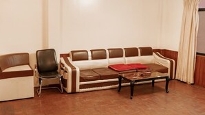 A room with a brown leather sofa, a black chair, and a small coffee table. - Yangchhen Peace Home Bed & Breakfast (Kathmandu)