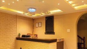 A reception area with a brick wall, a reception desk, a ceiling light fixture, and a reception sign. - Yangchhen Peace Home Bed & Breakfast (Kathmandu)