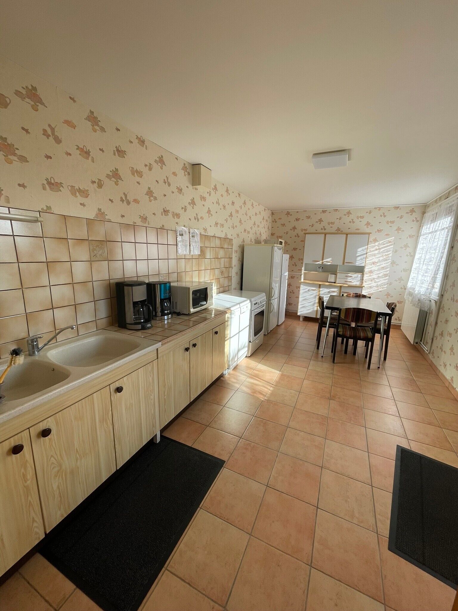 Una cocina compacta con lavamanos, estufa, microondas y refrigerador. Cuenta con una zona de comedor con mesa y sillas.