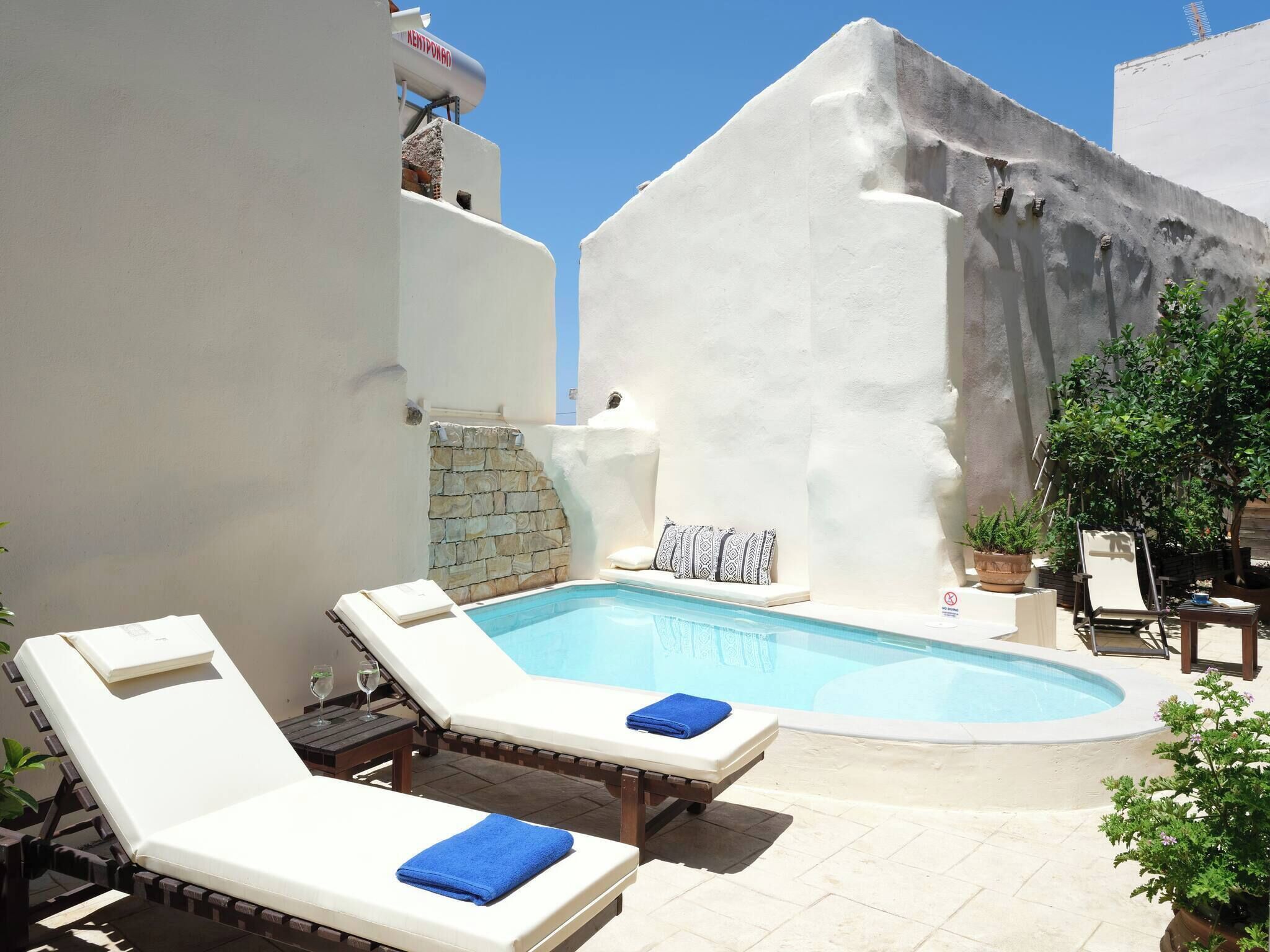 Un área de piscina con sillones de descanso y una pared de piedra.