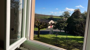 A window view of a residential area with a house, trees, and a clear sky. - Bed and Breakfast 'Chambre Verte' with Shared Terrace, Shared Garden and Wi-Fi (VERRIERES)