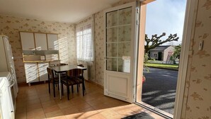A kitchen with a dining table and chairs, a refrigerator, and a sliding glass door leading outside. - Bed and Breakfast 'Chambre Verte' with Shared Terrace, Shared Garden and Wi-Fi (VERRIERES)
