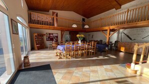 A spacious dining area with a high ceiling and wooden beams, a balcony with a railing, and a tiled floor. - Bed and Breakfast 'Chambre Saumon' with Shared Terrace, Shared Garden and Wi-Fi (VERRIERES)