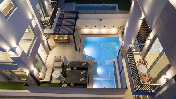 Un espace piscine aménagé sur le toit, avec un escalier menant à l’étage supérieur, des sièges extérieurs et une vue sur la piscine.