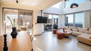 Un salon moderne doté d’un grand téléviseur, de sièges confortables et d’un balcon offrant une belle vue.