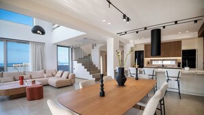 Un vaste espace de vie comprenant une table à manger en bois, des sièges confortables et une vue sur l’extérieur.