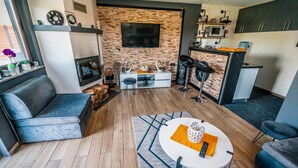 A modern living room with a fireplace, a TV, and a kitchen area with a microwave and bar stools. - Gorgeous home in Slavonski Brod with sauna (Slavonski Brod)