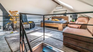 A loft bedroom with a sloped ceiling, a bed, a sofa, and a chair. - Gorgeous home in Slavonski Brod with sauna (Slavonski Brod)