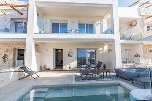 A modern two-story building with a rooftop pool area, outdoor seating, and a glass balustrade. - Lyra Suite (Panormo)