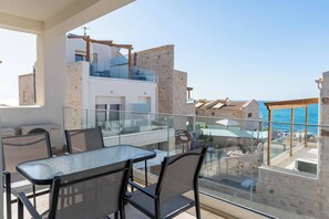 A balcony with a glass table and chairs, overlooking a pool and a clear blue sky. - Lyra Suite (Panormo)