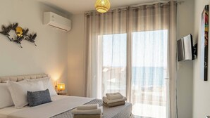 Hotellihuone, jossa on sänky, televisio, seinälle asennettu ilmastointilaite ja näkymä ulos.