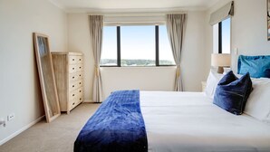 Une chambre d’hôtel avec un grand lit, une commode, une fenêtre avec des rideaux et une vue sur la ville.