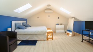 A bedroom with a bed, bedside table, dresser, mirror, TV stand, and skylights. - Guest Room “Ré” – Bright, Relaxing Space for Two (Virson)