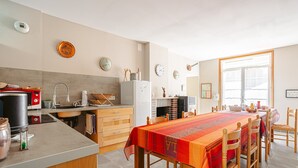 A modern kitchen with a dining table, chairs, and various kitchen appliances. - Guest Room “Ré” – Bright, Relaxing Space for Two (Virson)