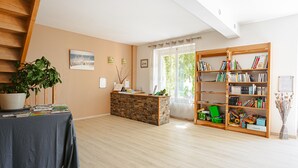 A room with a reception desk, a bookshelf, a potted plant, and a staircase. - Guest Room “Ré” – Bright, Relaxing Space for Two (Virson)