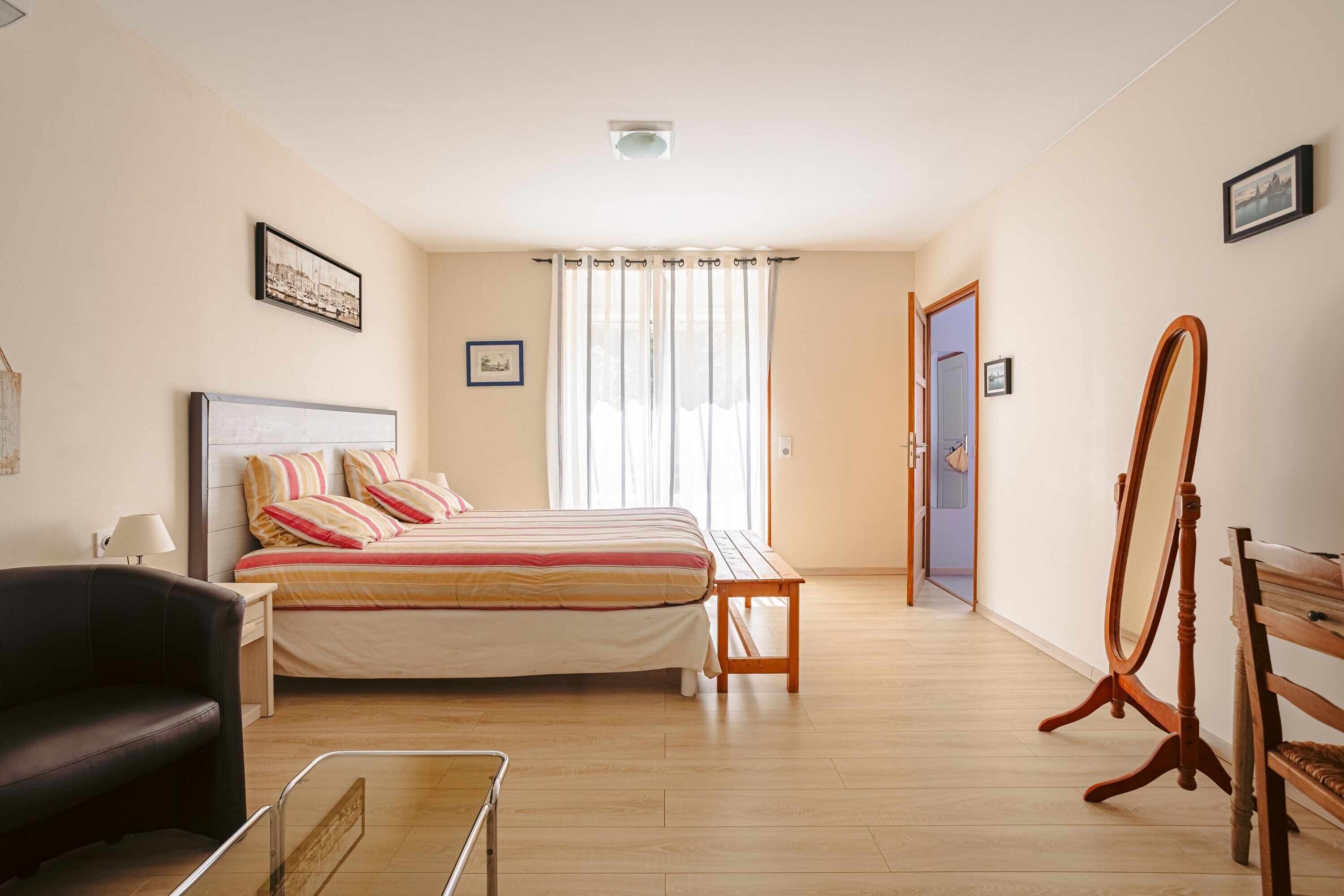 A bedroom with a bed, a desk, a chair, a dresser, and a mirror.