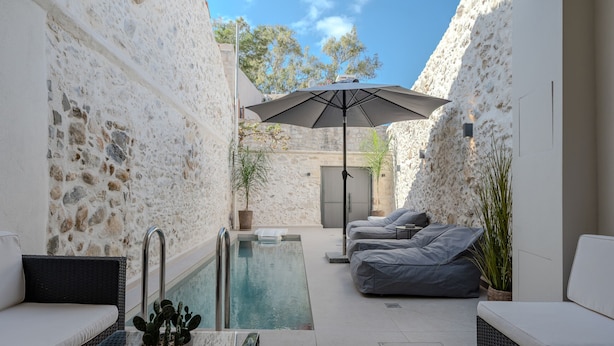A poolside area with stone walls, a pool, a covered seating area, and a potted plant. - Stone Project 2 a cozy retreat with private Pool (Pigi)
