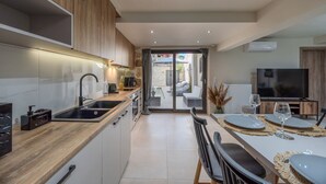A modern kitchen with a central island, built-in appliances, and a dining area with a table set for two. - Stone Project 2 a cozy retreat with private Pool (Pigi)