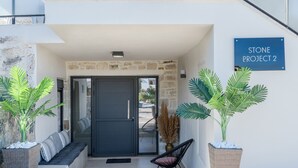 A modern entrance with a stone facade, a bench, and potted plants. - Stone Project 2 a cozy retreat with private Pool (Pigi)