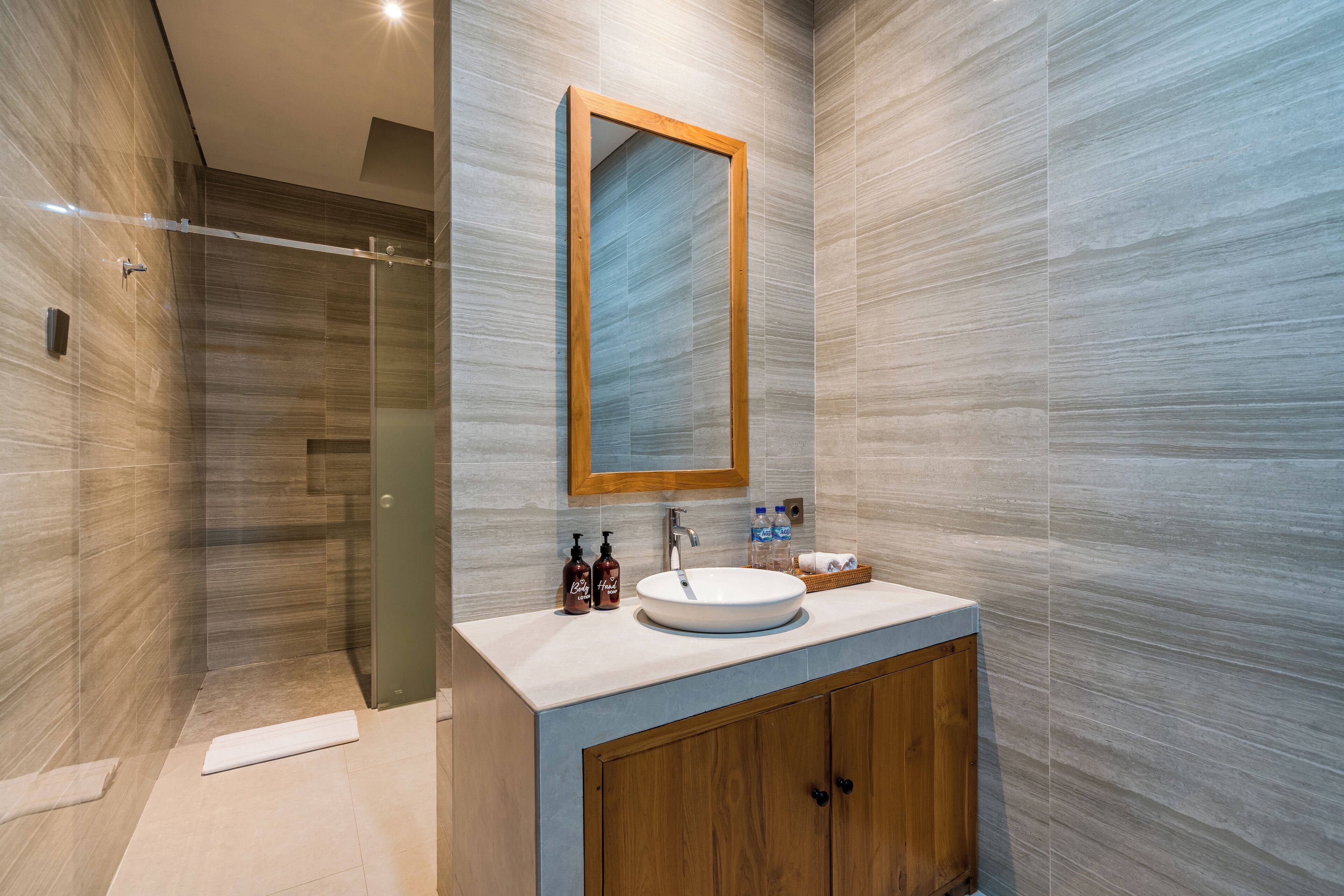 Une salle de bain moderne avec un grand miroir, un lavabo rond et des meubles en bois.