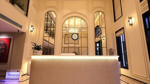 Un área de recepción con mostrador, amplias ventanas arqueadas y una escalera al fondo.