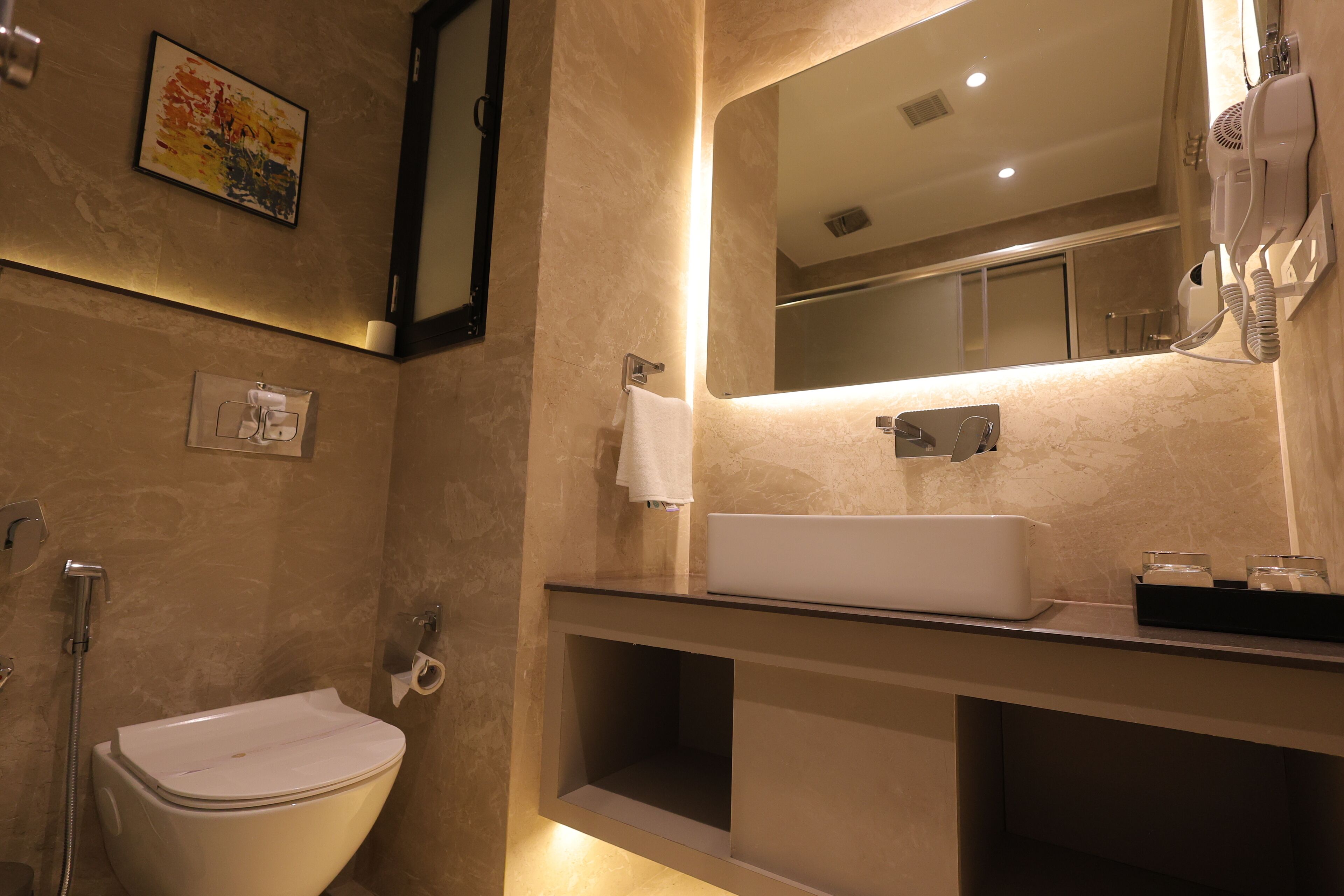 A modern bathroom with a toilet, sink, and a hairdryer mounted on the wall.