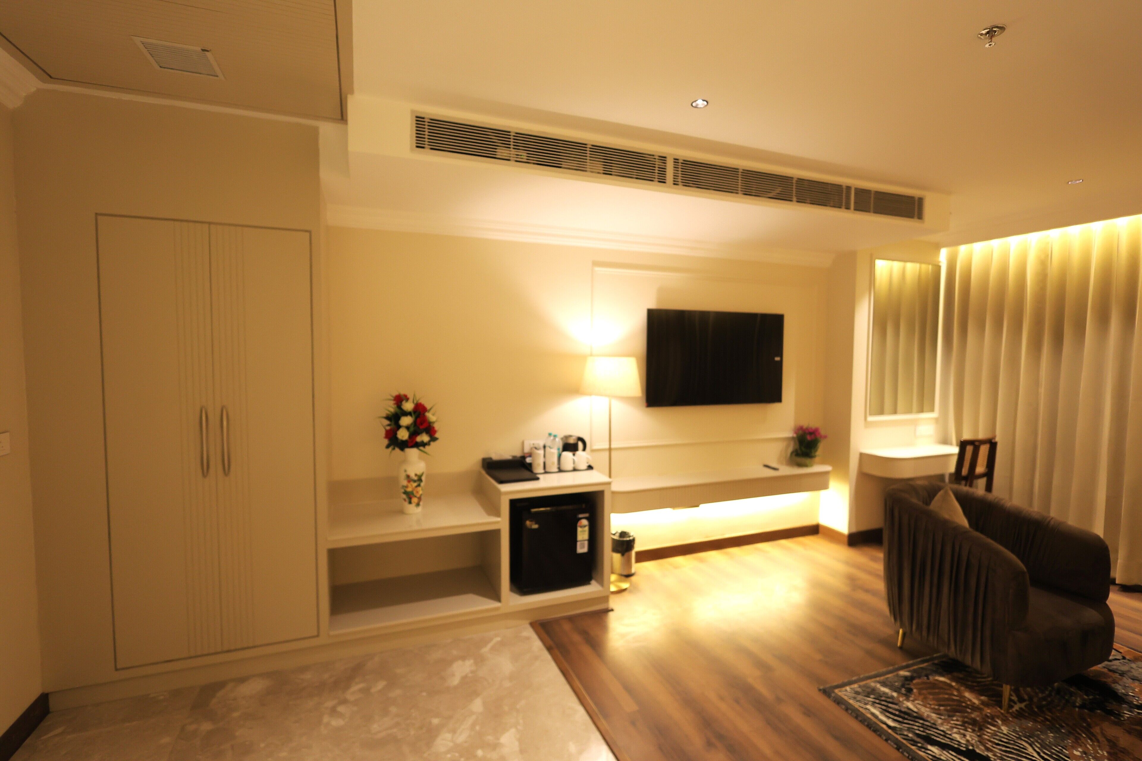 A modern living room with a sofa, a TV mounted on the wall, a cabinet, and a small table with a lamp.
