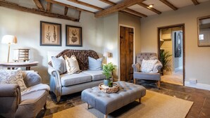 A cozy living room with a grey sofa, a matching armchair, and a wooden coffee table. - Two Cottages near Stratford-upon-Avon (Clifford Chambers)