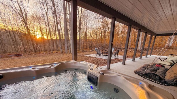 Een bubbelbad met uitzicht op een bos bij zonsondergang.