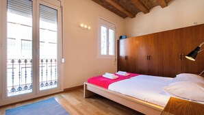 A bedroom with a wooden bed, a nightstand, a wardrobe, and a window with blinds. - Ramon Turró - Nice apartment in Poble Nou near the beach (Barcelona)