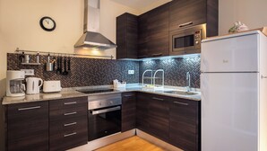 A modern kitchen with dark wood cabinets, a stainless steel microwave, a built-in oven, and a refrigerator. - Ramon Turró - Nice apartment in Poble Nou near the beach (Barcelona)