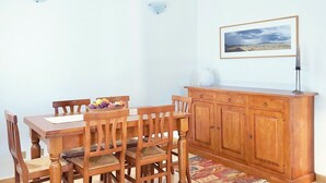 Een eethoek met een houten tafel en stoelen, een kast en een ingelijste foto aan de muur.
