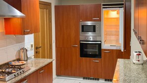 Una cocina con armarios de madera, horno empotrado, microondas, estufa a gas y un tostador.