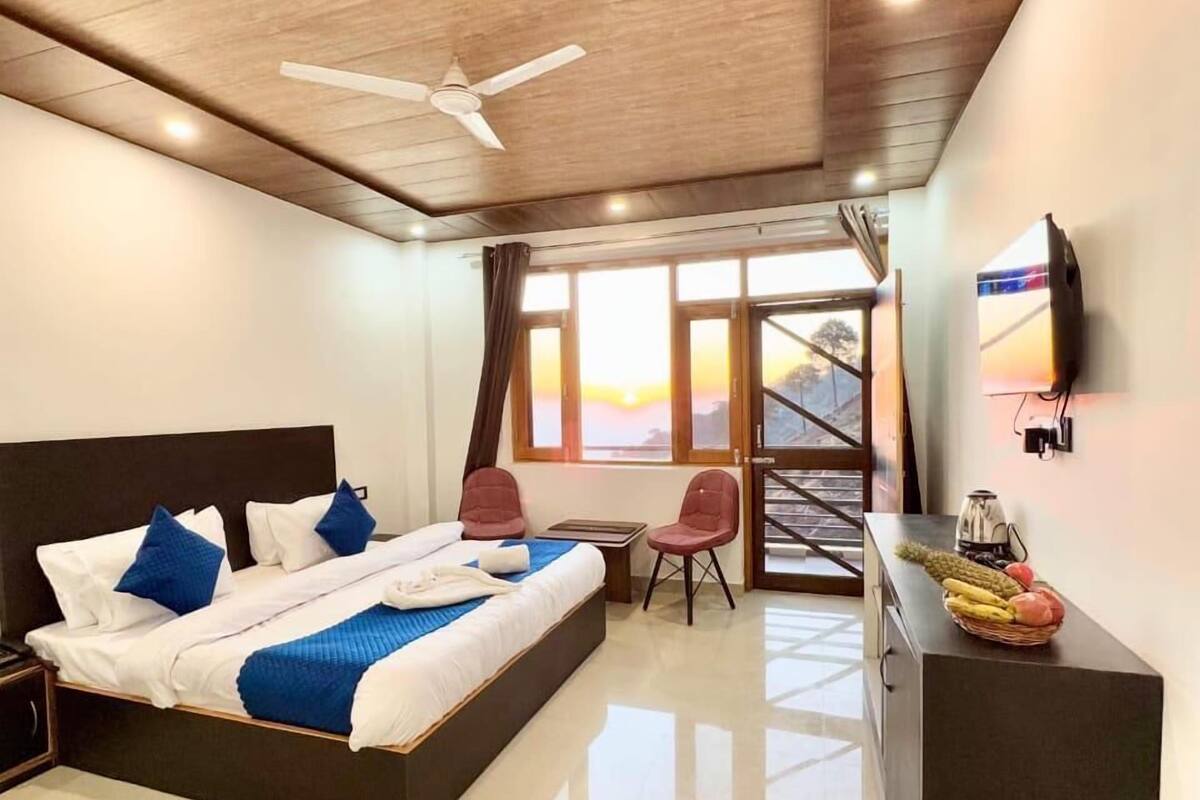 Une chambre d’hôtel moderne, dotée d’un grand lit, d’un bureau, d’une chaise et d’un téléviseur fixé au mur.