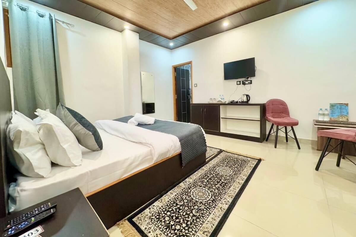 Une chambre d’hôtel moderne équipée d’un lit, d’un bureau, d’une chaise, d’une télévision et d’un ventilateur de plafond.