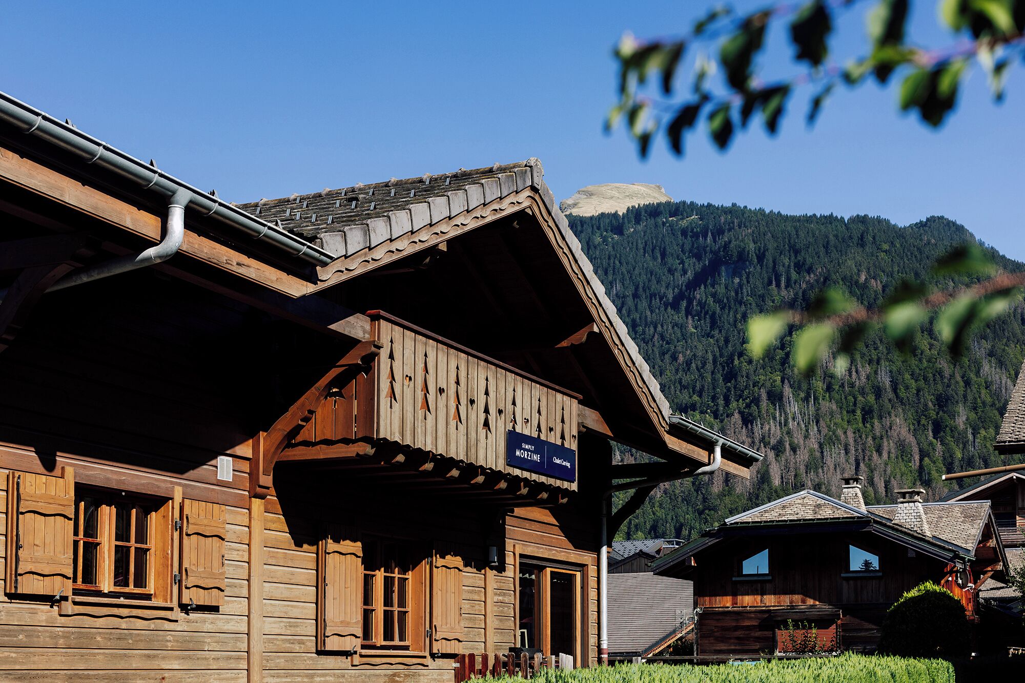 Een houten chalet met een balkon, een bord met restaurant erop en een bergachtige achtergrond.