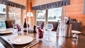 Une table à manger dressée avec des assiettes, des couverts, des verres à vin et une bouteille de vin.
