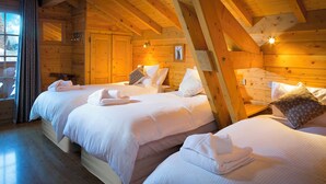 Une pièce aménagée dans le style d’un chalet en rondins, avec trois lits, des murs en bois et un plafond en pente.