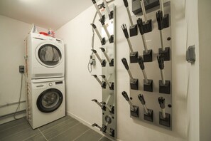 A laundry area with a stacked washer and dryer, a wall-mounted drying rack, and a power outlet.