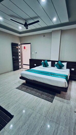A modern hotel room with a large bed, a ceiling fan, and a view of the outside. - The Quade Villa By Spandan Holiday Homes (Varanasi)