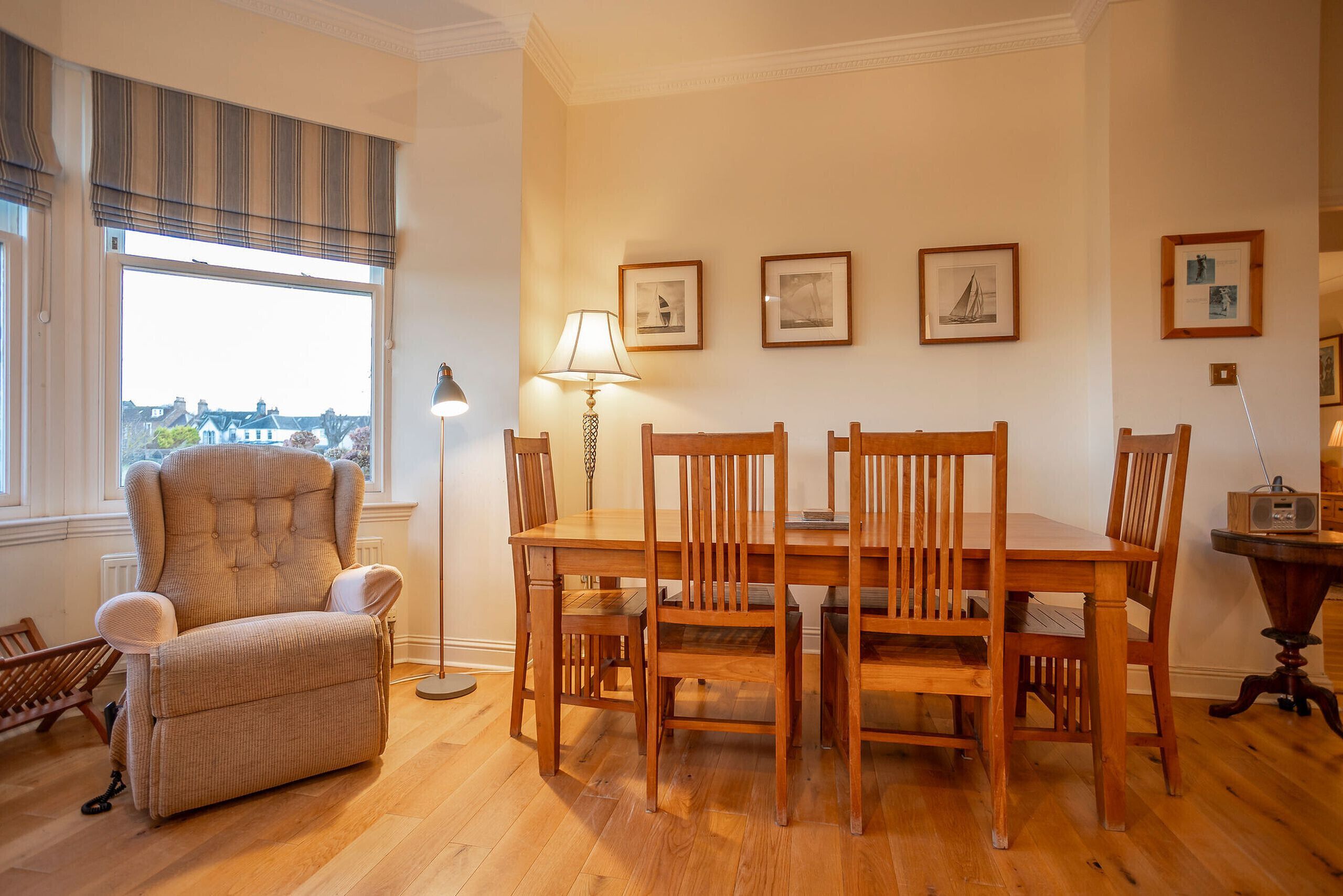 A dining area with a wooden table and chairs, a cushioned armchair, and a floor lamp.