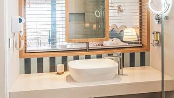 Une salle de bain avec un grand miroir, un lavabo, une douche et des toilettes.