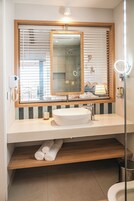 Ein Badezimmer mit großem Spiegel, Waschbecken, Dusche und Toilette.