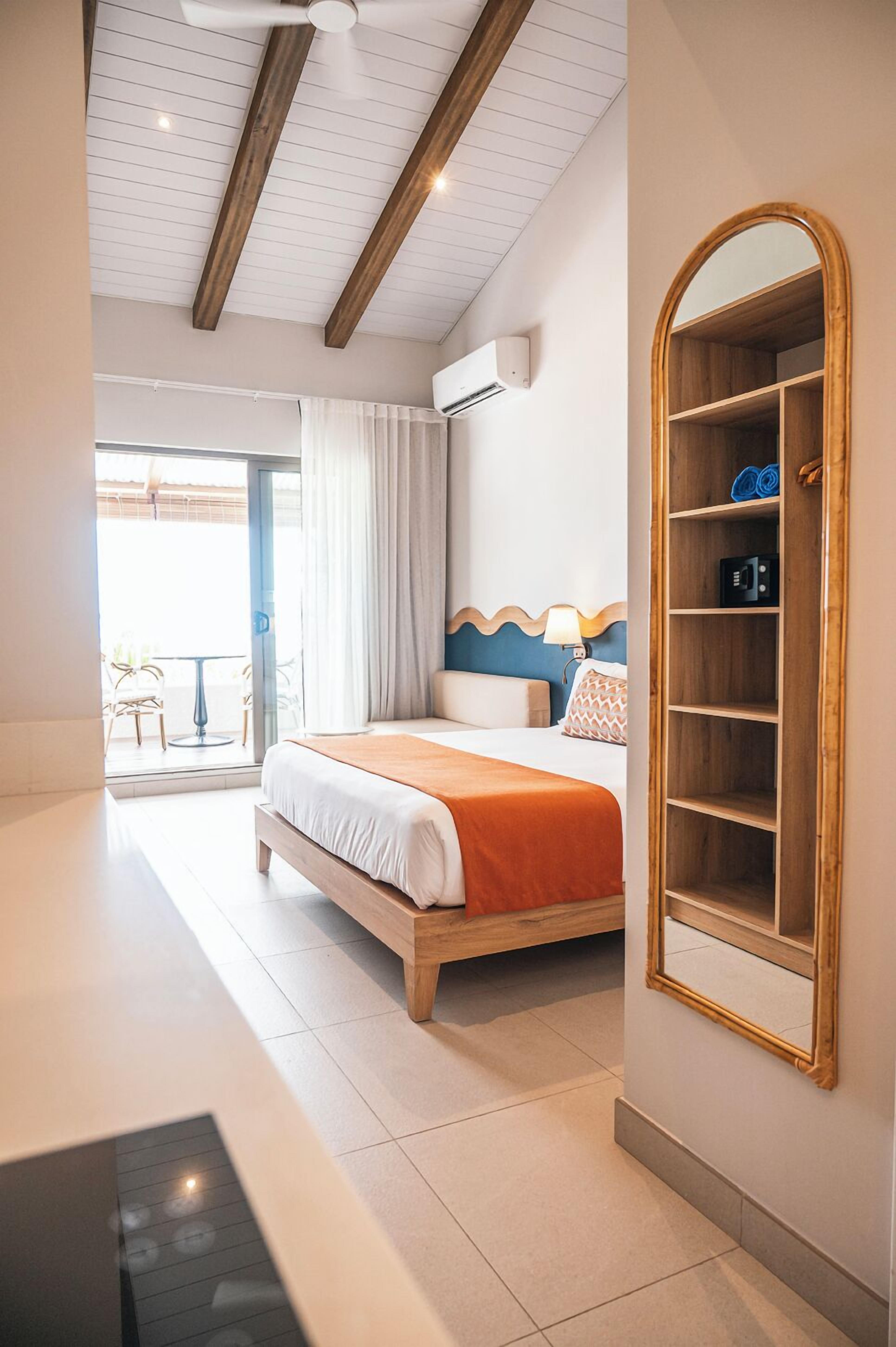 Habitación de hotel con cama, armario, ventilador de techo y vistas al exterior.