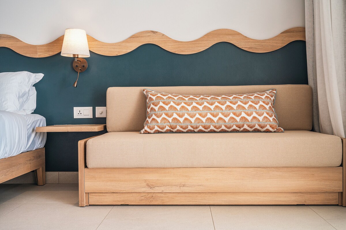 A bedroom with a bed, a nightstand, a lamp, and a patterned pillow.