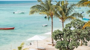 Una playa con palmeras, una orilla arenosa y varios barcos en el agua.
