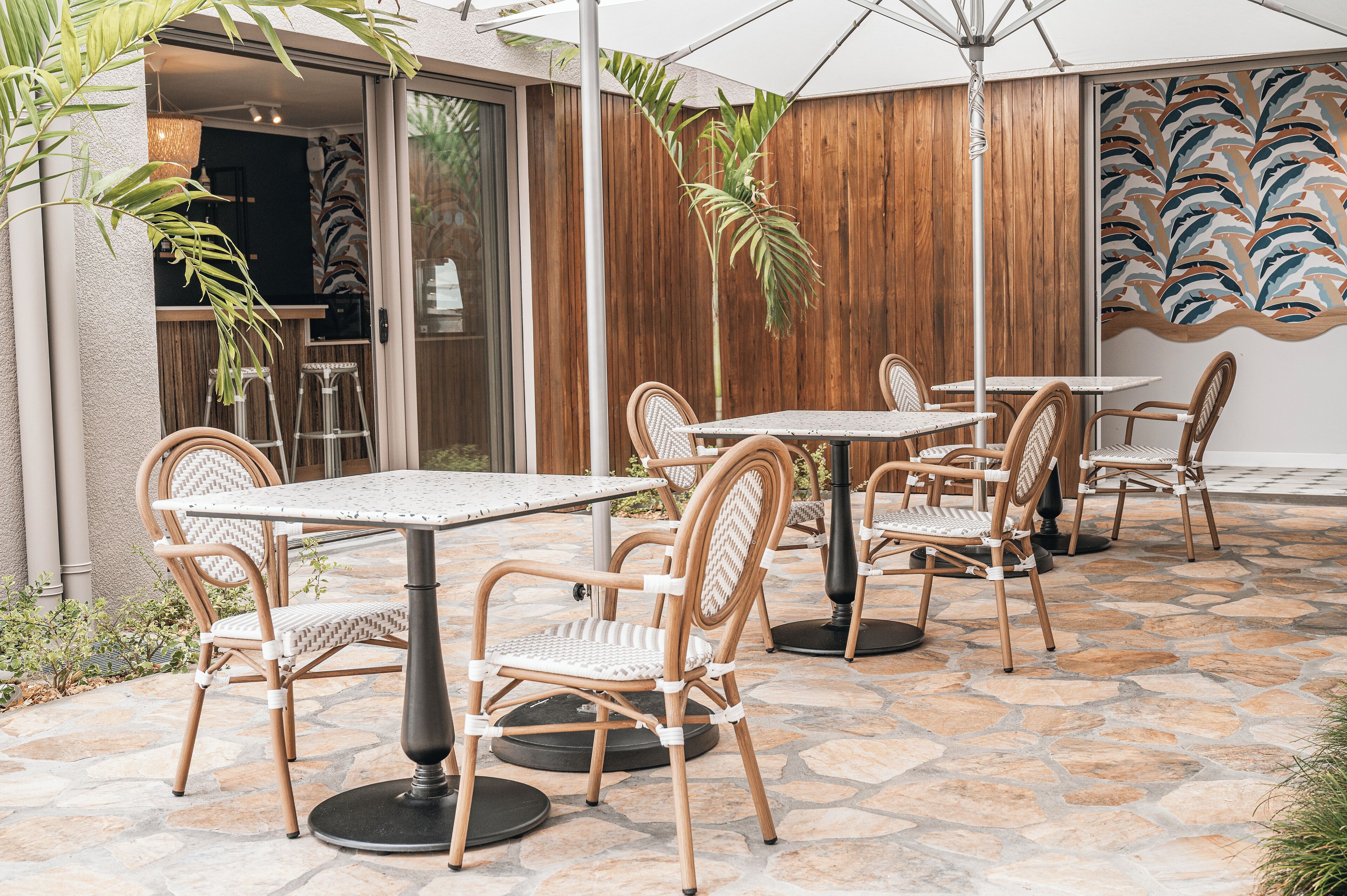 An outdoor patio area with stone flooring, wicker chairs, and tables.