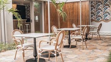 An outdoor patio area with stone flooring, wicker chairs, and tables.