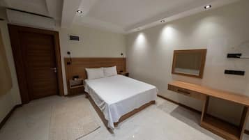 A bedroom with a bed, bedside tables, a mirror, and a wooden dresser.