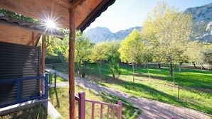 A covered outdoor area with a brick pathway leading to a grassy field and trees. - Welt bungslows  (Konyaalti)